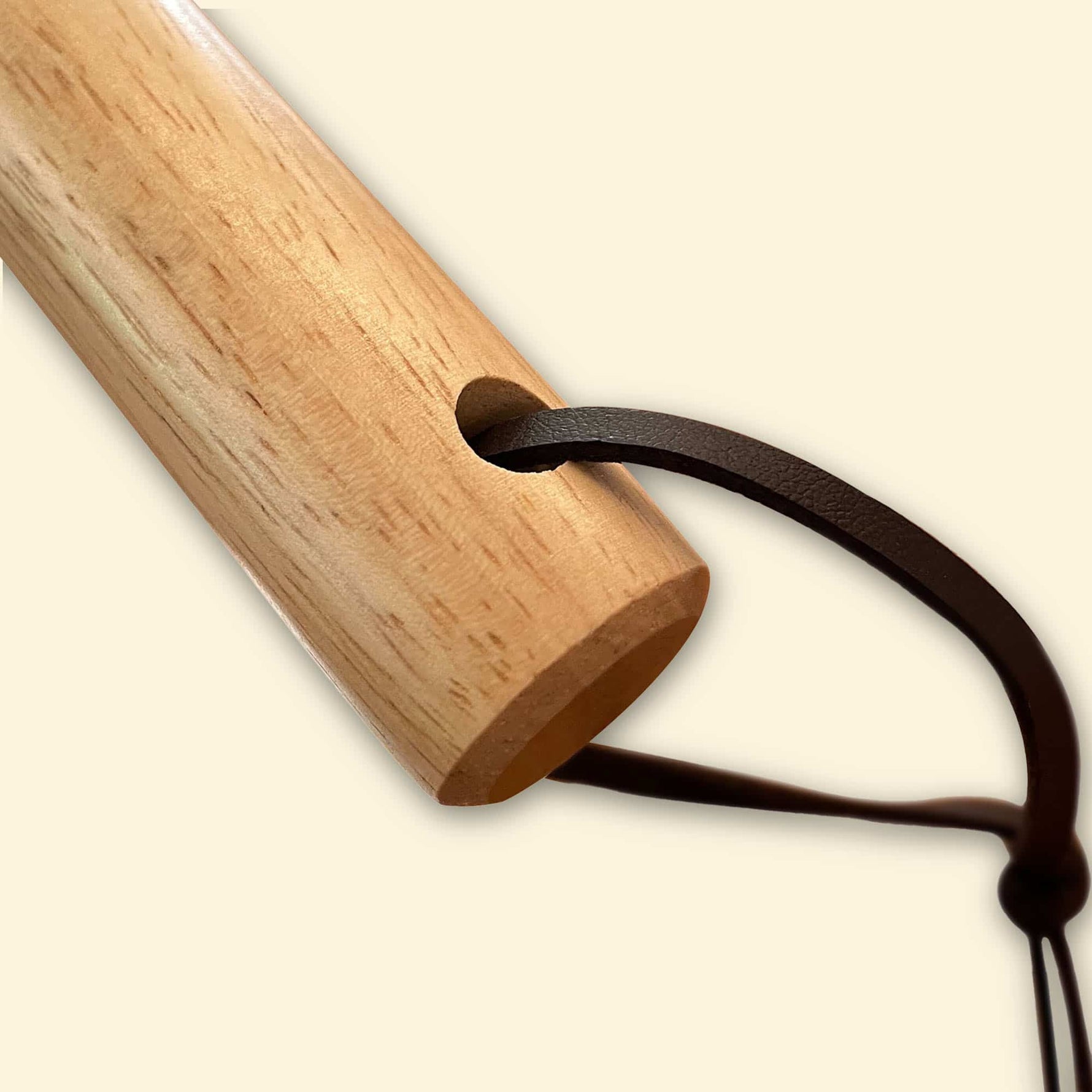 Gros plan sur l’extrémité en bois du manche de la pelle à pizza XL, montrant le trou traversant et la lanière en cuir pour suspendre l’ustensile.